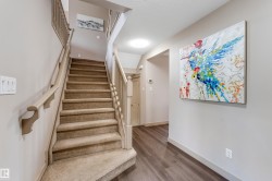 The property features a staircase with carpeted steps and light-colored banisters, complemented by a hallway with wood-style flooring - 