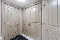 Entryway featuring a panel door, double bifold doors with vertical planking, and crown molding - 