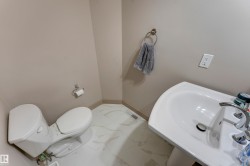 Well-appointed bathroom featuring a pedestal sink, a toilet, and patterned flooring - 