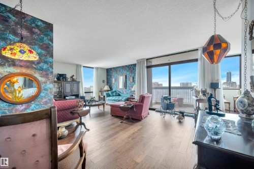 Spacious living area featuring wood-finish flooring, full-height windows, balcony access, and high ceilings - 1603 10025 113 Street, Edmonton, AB - Indoor Photo Showing Living Room