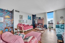 Spacious living area featuring large windows with urban scenery, wood-finish flooring, and crown molding - 