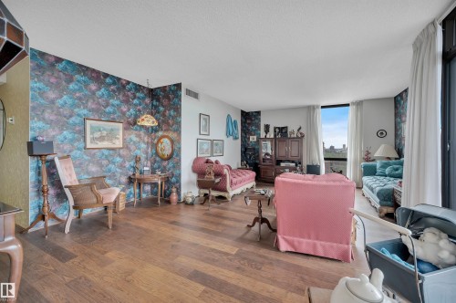 Spacious interior featuring wood-finish flooring, accent walls with patterned wallpaper, and large windows with vertical drapery - 1603 10025 113 Street, Edmonton, AB - Indoor