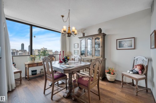 Dining area featuring expansive window, wood-finish flooring, and a multi-arm chandelier - 1603 10025 113 Street, Edmonton, AB - Indoor Photo Showing Dining Room