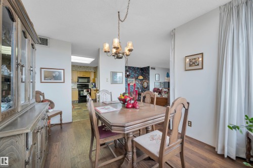 Dining area featuring wood-finish flooring, a traditional chandelier, and light-colored walls - 1603 10025 113 Street, Edmonton, AB - Indoor Photo Showing Dining Room