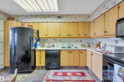 Kitchen featuring wood-finish cabinetry, solid surface countertops, and integrated black appliances - 