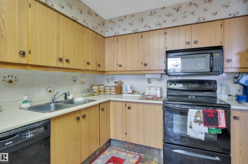 Kitchen featuring light wood-finish cabinetry, white countertops, and a white tiled backsplash with decorative accents - 1603 10025 113 Street, Edmonton, AB - Indoor Photo Showing Kitchen With Double Sink