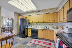 Kitchen with wood-finish cabinetry, solid surface countertops, and a tile backsplash - 