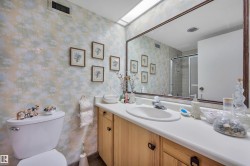 Bathroom featuring a vanity with an integrated sink, a large wall-mounted mirror, and wood-finish cabinetry - 