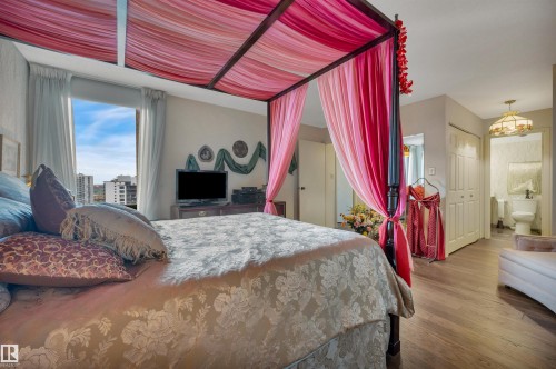 Bedroom featuring wood-finish flooring, a full-height window, and direct access to a bathroom - 1603 10025 113 Street, Edmonton, AB - Indoor Photo Showing Bedroom