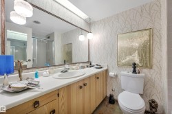 Bathroom featuring a vanity with wood-finish cabinetry, a single basin sink, and a large wall-mounted mirror - 