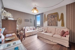 Living area featuring wood-finish flooring, vertical striped wallpaper, and a large window with vertical blinds - 