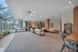Spacious common area featuring a full-length glass sunroom, track lighting, neutral carpeting, and multiple seating zones - 