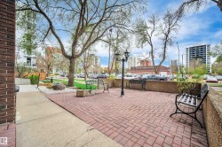 Brick paver patio area featuring a decorative lamppost and multiple wrought iron benches - 