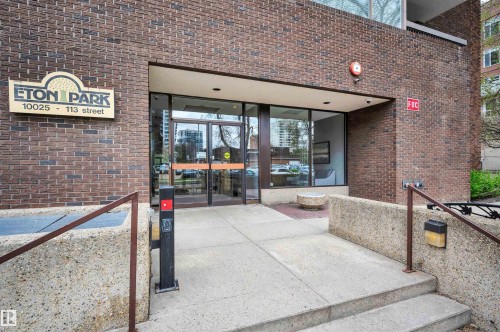 Brick facade building entrance with glass doors, concrete steps, and integrated handrails - 1603 10025 113 Street, Edmonton, AB - Outdoor