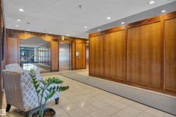 Lobby area featuring wood-paneled walls, multiple elevators with stainless steel doors, recessed lighting, and tile flooring - 