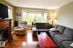 Living area featuring wood-finish flooring, a bay window, a built-in fireplace with a carved wood mantel, and light green walls - 