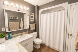 Full bathroom featuring a single vanity with a white countertop and base cabinetry, a standard toilet, and a tub/shower combination with a shower curtain rod - 
