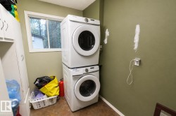 Dedicated laundry space featuring a window, wood-finish flooring, a stacked washer and dryer, and built-in white cabinetry - 
