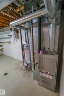 Mechanical room featuring a water heater, furnace, and exposed ceiling joists - 