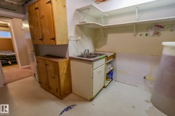 Utility area featuring a double basin sink, white lower cabinetry, and open shelving - 
