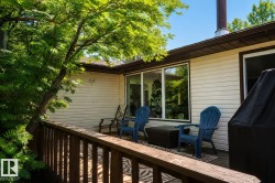 Outdoor deck featuring a wood railing, siding exterior, large windows, and a prominent exhaust pipe - 
