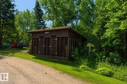 Utility shed with multiple bays and a gravel driveway set amidst mature trees - 