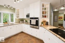 Kitchen featuring white cabinetry, built-in stainless steel appliances, granite countertops, and a bay window - 