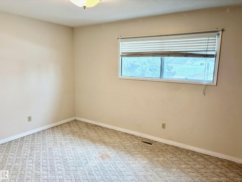 This room features light-colored walls, patterned carpet flooring, and a window with horizontal blinds - 15208 92 Street, Edmonton, AB - Indoor Photo Showing Other Room