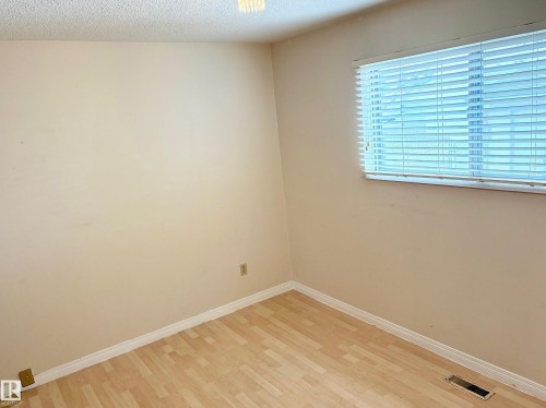 This room features light-colored walls and wood-style flooring, complemented by a window with horizontal blinds, providing natural light - 15208 92 Street, Edmonton, AB - Indoor Photo Showing Other Room