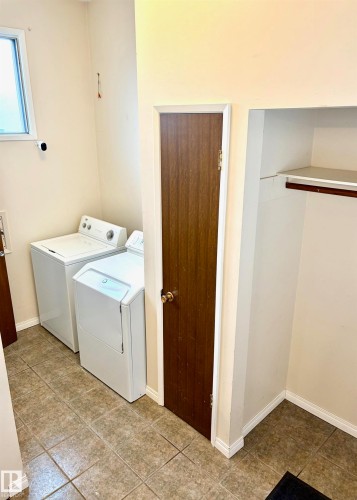 Laundry area featuring tiled flooring, a window, and an integrated closet with a hanging rod and shelving - 15208 92 Street, Edmonton, AB - Indoor Photo Showing Laundry Room