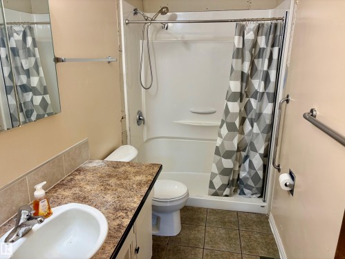 Bathroom featuring a vanity with an integrated sink and a shower with a patterned curtain - 15208 92 Street, Edmonton, AB - Indoor Photo Showing Bathroom