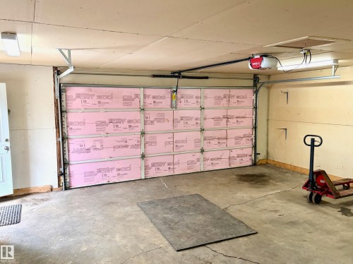 The property features a garage with a ceiling-mounted garage door opener and fluorescent lighting - 15208 92 Street, Edmonton, AB - Indoor Photo Showing Garage