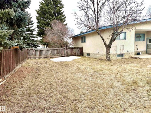 The property features a spacious yard with a wooden fence and mature trees - 15208 92 Street, Edmonton, AB - Outdoor