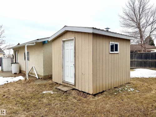 The property includes an exterior shed with vertical siding, a white door, and a single window - 15208 92 Street, Edmonton, AB - Outdoor With Exterior