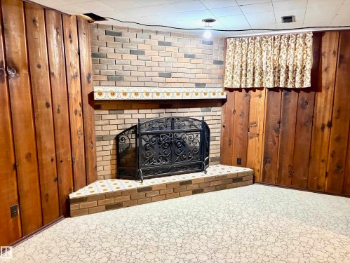 Living area featuring a brick fireplace with a decorative screen and an ornate tiled hearth - 15208 92 Street, Edmonton, AB - Indoor With Fireplace