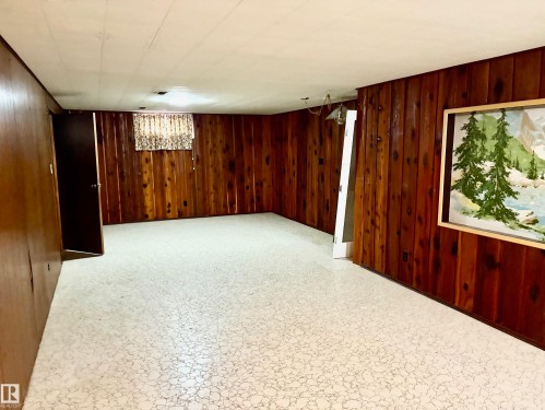 This room features wood paneling, a patterned floor, and a window with a curtain - 15208 92 Street, Edmonton, AB - Indoor Photo Showing Other Room