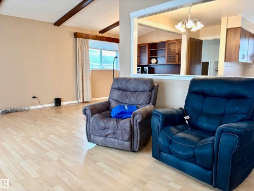 Living area featuring light-toned flooring, exposed ceiling beams, and a window for natural light - 15208 92 Street, Edmonton, AB - Indoor Photo Showing Living Room