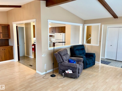 Living area featuring light wood flooring, exposed wood ceiling beams, and a partial wall with openings - 15208 92 Street, Edmonton, AB - Indoor Photo Showing Living Room