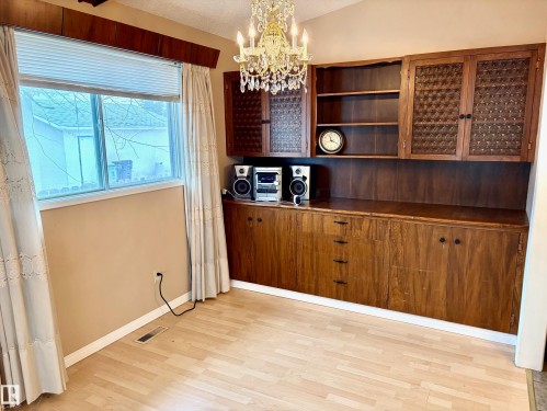 This room features light-toned flooring, a window with blinds and curtains, and built-in wooden cabinetry with storage and shelving - 15208 92 Street, Edmonton, AB - Indoor Photo Showing Other Room