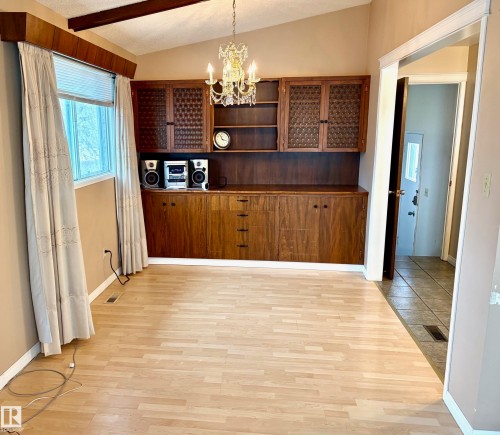 The room features light-toned flooring, a vaulted ceiling with exposed wood beams, and a large window with blinds and curtains - 15208 92 Street, Edmonton, AB - Indoor Photo Showing Other Room