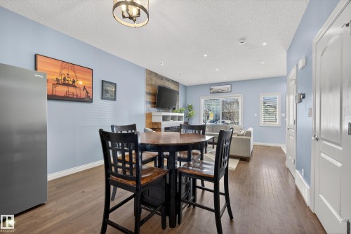 Open-concept living space featuring wood-finish flooring, light blue wall tones, white trim, and a shiplap accent wall - 7074 Cardinal Way, Edmonton, AB - Indoor Photo Showing Dining Room