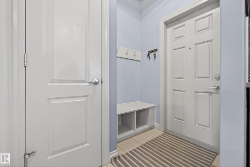 Entryway featuring light blue walls, white paneled doors with chrome hardware, and light-toned tile flooring - 7074 Cardinal Way, Edmonton, AB - Indoor Photo Showing Other Room