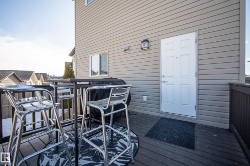 Exterior deck with composite decking, featuring a privacy railing, decorative outdoor lighting, and a white paneled entry door - 7074 Cardinal Way, Edmonton, AB - Outdoor With Exterior