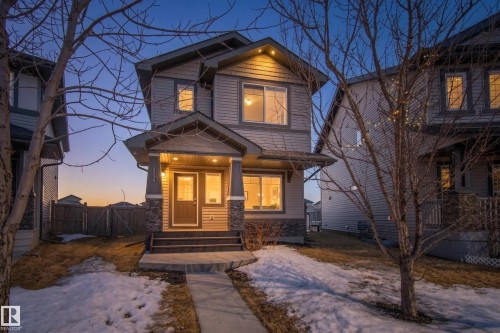 Two-story residence featuring light gray siding, dark trim, and stone accents on the front facade - 7074 Cardinal Way, Edmonton, AB - Outdoor