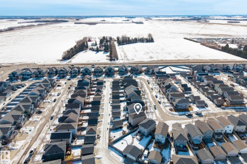Residential neighborhood featuring an array of detached homes with dark shingle roofs, situated near agricultural fields - 7074 Cardinal Way, Edmonton, AB - Outdoor With View