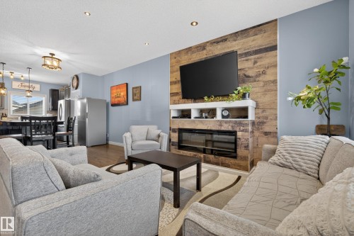 Contemporary living area featuring a rustic wood-plank accent wall and a built-in electric fireplace - 7074 Cardinal Way, Edmonton, AB - Indoor Photo Showing Living Room With Fireplace