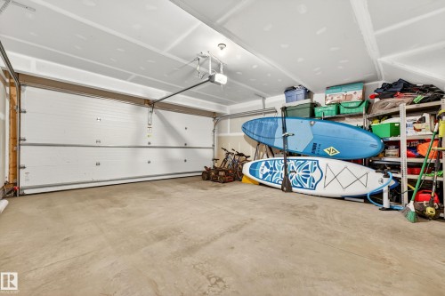Spacious garage featuring a concrete floor, high ceilings, automatic garage door opener, and ample storage space along the far wall - 38 Jensen Gate, St. Albert, AB - Indoor Photo Showing Garage