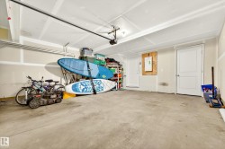 Spacious garage featuring a concrete floor, overhead lighting, and white panel doors - 