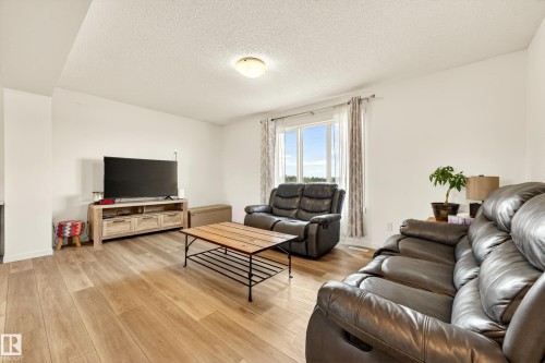 Living area with wood-finish flooring, white walls, and a large window - 38 Jensen Gate, St. Albert, AB - Indoor Photo Showing Living Room