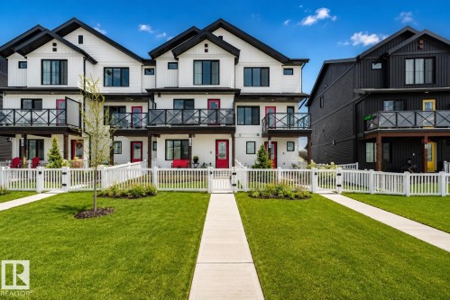 Modern townhome exterior with crisp white siding and contrasting black trim - 38 Jensen Gate, St. Albert, AB - Outdoor With Balcony With Facade